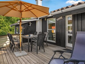 Une terrasse avec une table et des chaises, un grand parasol et un bâtiment à l’extérieur sombre, sur lequel on peut lire l’inscription « Lugano ».
