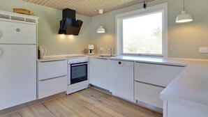 Eine moderne Küche mit weißen Schränken, einem eingebauten Backofen, einer Spülmaschine und einem Fenster für natürliches Licht.