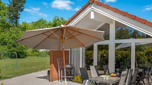 A covered patio with a table and chairs, a grill, and a large umbrella.