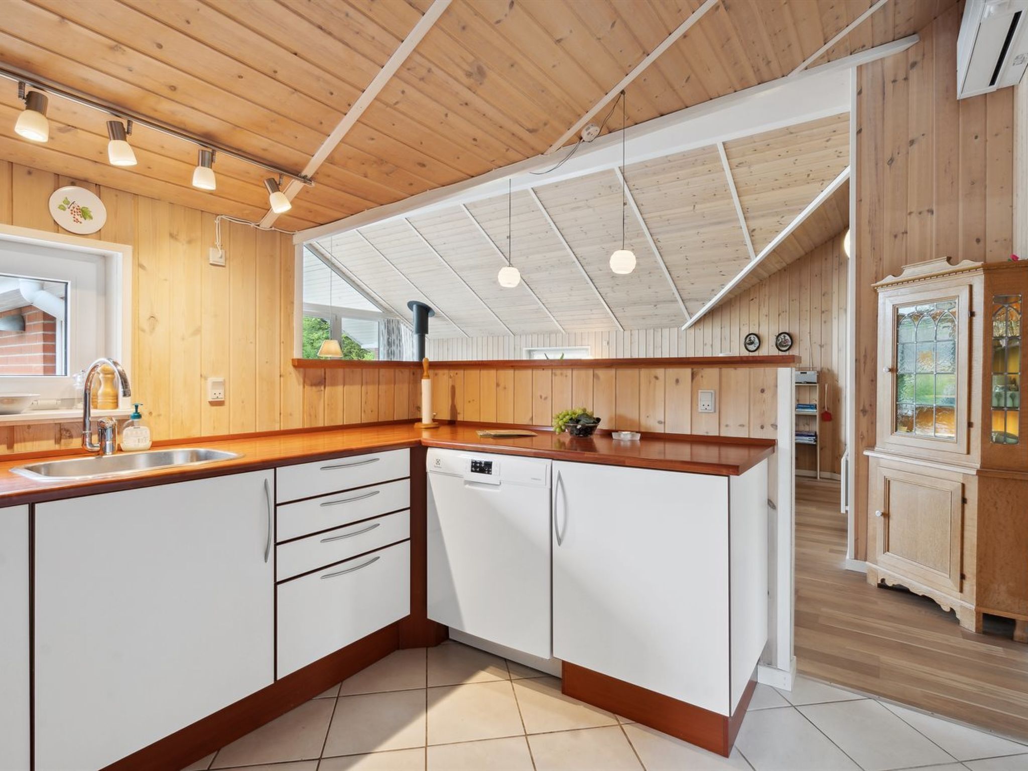 A modern kitchen with wooden cabinets, a dishwasher, and a large island with a sink.