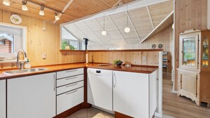 A modern kitchen with wooden cabinets, a dishwasher, and a large island with a sink.