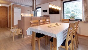 Een gezellige keuken met houten kastjes, een rvs afzuigkap en een eethoek met een tafel gedekt voor vier personen.