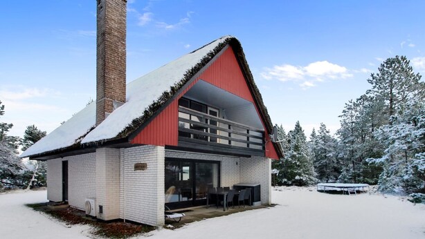 Een chalet met een rood dak, schoorsteen en een overdekt terras.