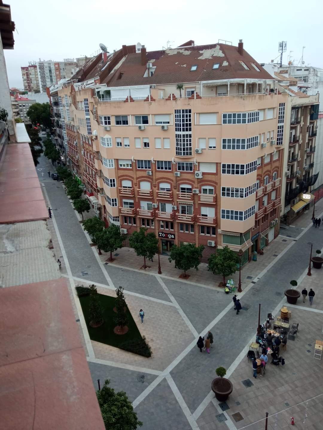 A multi-story building with a central courtyard, surrounded by trees and a pedestrian area.