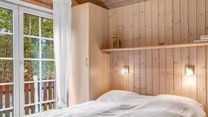 A bedroom with a wooden paneled wall, a bed with a white bedspread, a window with white curtains, and a small shelf with a lamp. - "Orpah" - 2.5km from the sea by Interhome (Rømø)