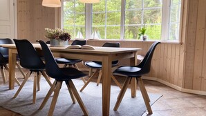 A dining area with a wooden table and chairs, large windows, and hanging pendant lights. - "Orpah" - 2.5km from the sea by Interhome (Rømø)