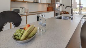 Eine moderne Küche mit Granitabdeckung, Edelstahlgeräten und einer Wand mit Backsteinverkleidung.