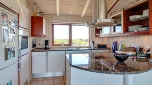 A modern kitchen with a large island, white cabinetry, and a view through the window. - "Alim" - 300m from the sea by Interhome (Rømø)