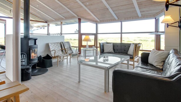 A spacious living area with a modern fireplace, comfortable seating, and large windows offering a view of the outdoors. - "Alim" - 300m from the sea by Interhome (Rømø)