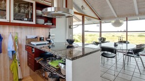 A modern kitchen with granite countertops, a built-in stove, and a dining area with a round table and chairs. - "Alim" - 300m from the sea by Interhome (Rømø)