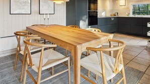 Une cuisine moderne avec une table et des chaises en bois, un meuble noir et une fenêtre donnant sur un espace verdoyant.