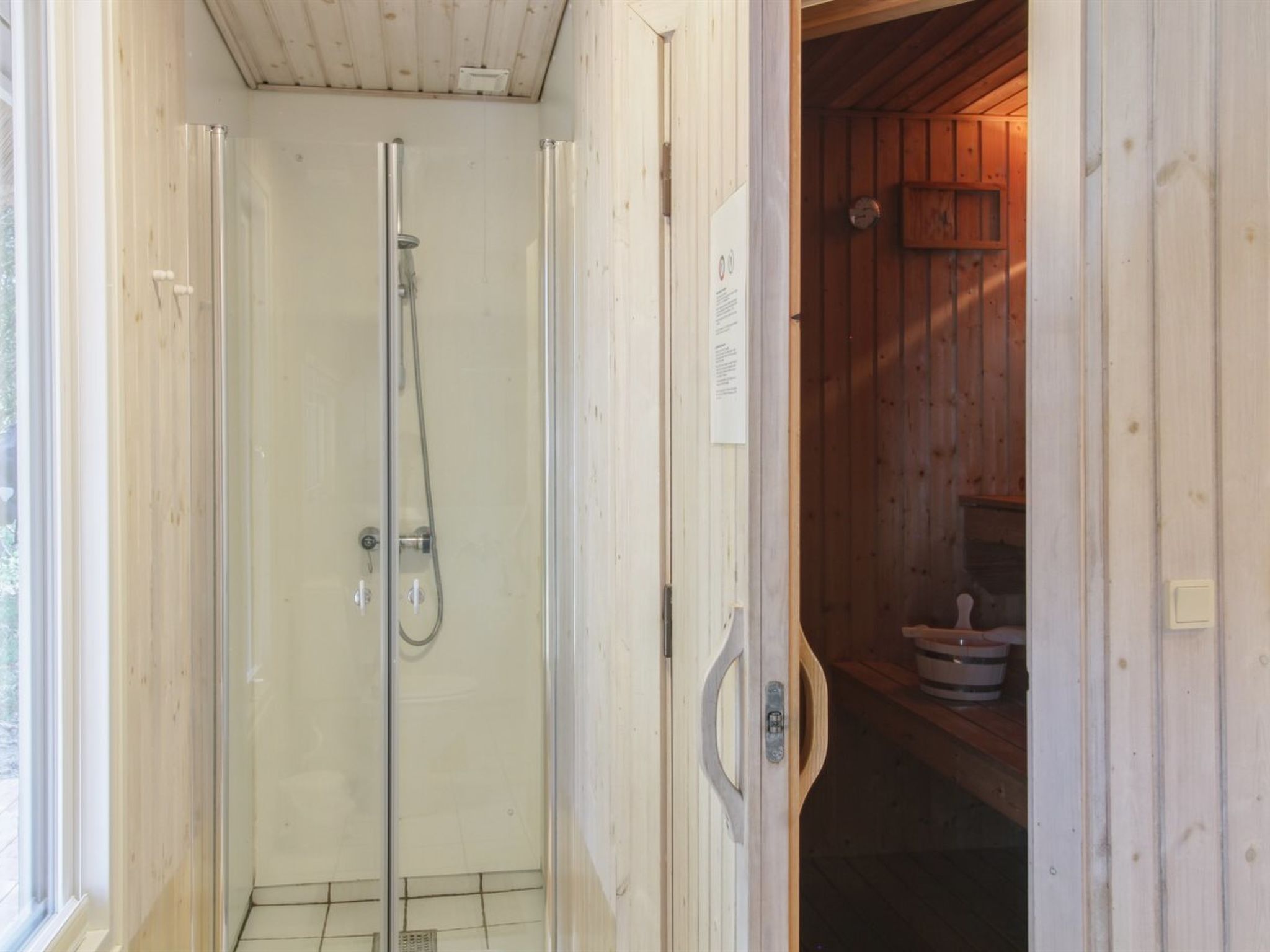 A wooden cabin with a glass-enclosed shower area and a visible wooden door.