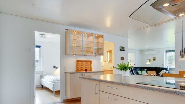 Una cocina moderna con una isla central, armarios integrados y vistas al dormitorio contiguo.