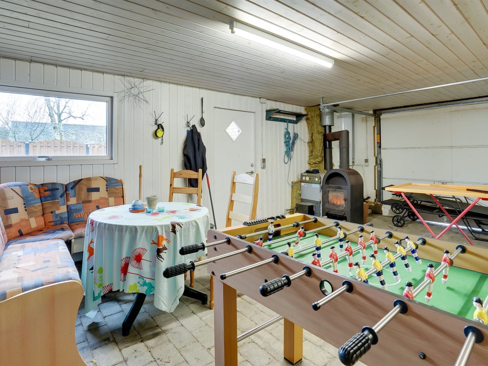 A cozy indoor space with a foosball table, a sofa, and a table with a tablecloth.