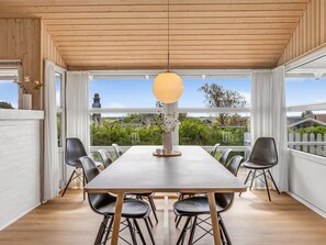 A dining area with a long table and chairs, large windows with curtains, and a hanging light fixture. - "Gudmar" - 500m from the sea by Interhome (Rømø)