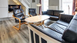 A modern living room with a sofa, two chairs, a wooden coffee table, and a kitchen area with a stove and cabinets. - "Anouk" - 1.7km from the sea by Interhome (Rømø)