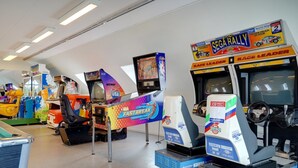 Eine Reihe von Arcade-Rennspielen mit einem 'SEGA RALLY'-Schild darüber.