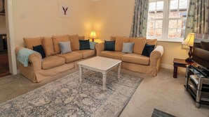 A living room with beige sofas, a white coffee table, and a patterned rug. - Wolds Way (Driffield)