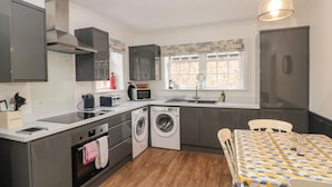 A compact kitchen with a washing machine, a microwave, and a refrigerator. - Wolds Way (Driffield)