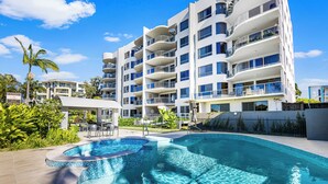 Un hôtel moderne doté d’une piscine, de nombreux balcons et d’une végétation luxuriante.