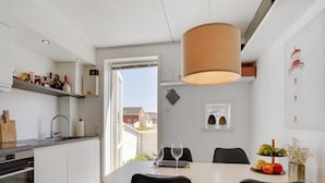 Una cocina moderna con comedor, que cuenta con un gran ventanal, una lámpara colgante y vistas del barrio.