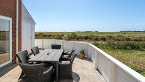 Un patio con una mesa y sillas, una planta en maceta y vistas a un campo verde.
