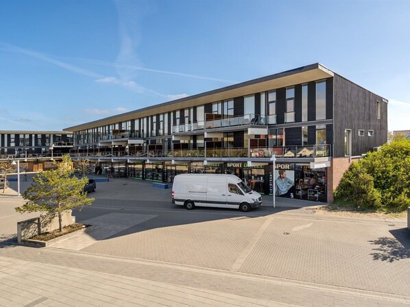 A modern multi-story building with a white van parked in front.