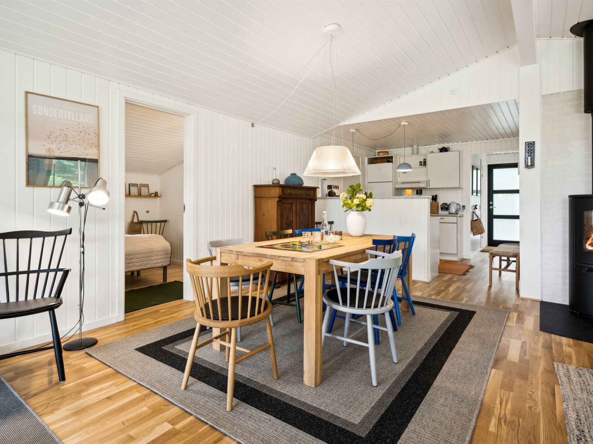 Ein geräumiges Wohnzimmer mit einem Holzessttisch, blauen und hölzernen Stühlen, einer großen Lampe und einem Kamin.