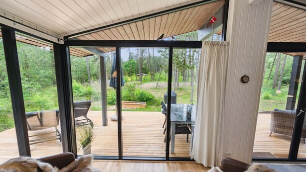 A modern interior with large sliding glass doors leading to an outdoor deck. Inside, there are two leather sofas facing a small round table with candles. - "Santuzza" - 3.9km from the sea by Interhome (Rømø)