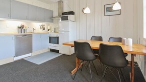 Une cuisine moderne avec des meubles gris, une table à manger en bois et des chaises noires.