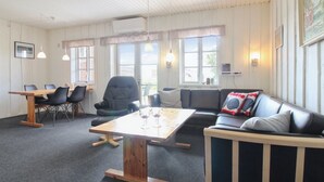 Une pièce comprenant une table en bois, des chaises en cuir noir, un canapé en cuir noir et un fauteuil en cuir noir.