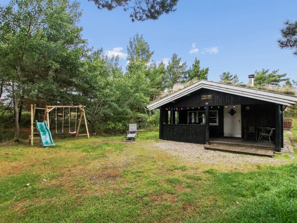 En stuga med en veranda, en gunga och en stol.