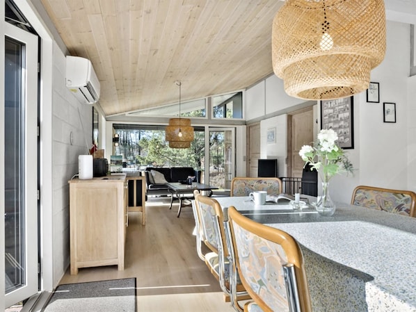 A modern kitchen with a large island, wooden cabinetry, and a hanging woven light fixture.