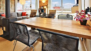 Un salon chaleureux avec une table en bois, des fauteuils en osier noir, un canapé et une cheminée.
