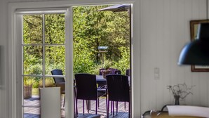 Une terrasse extérieure avec une table et des chaises, une pergola et une vue sur la verdure.