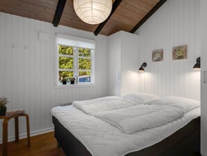 Ein Schlafzimmer mit Bett, Fenster und Wandleuchten.