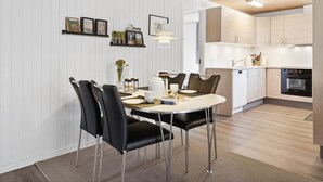 Una cocina moderna con armarios blancos, un horno negro y un comedor con una mesa redonda y sillas negras.