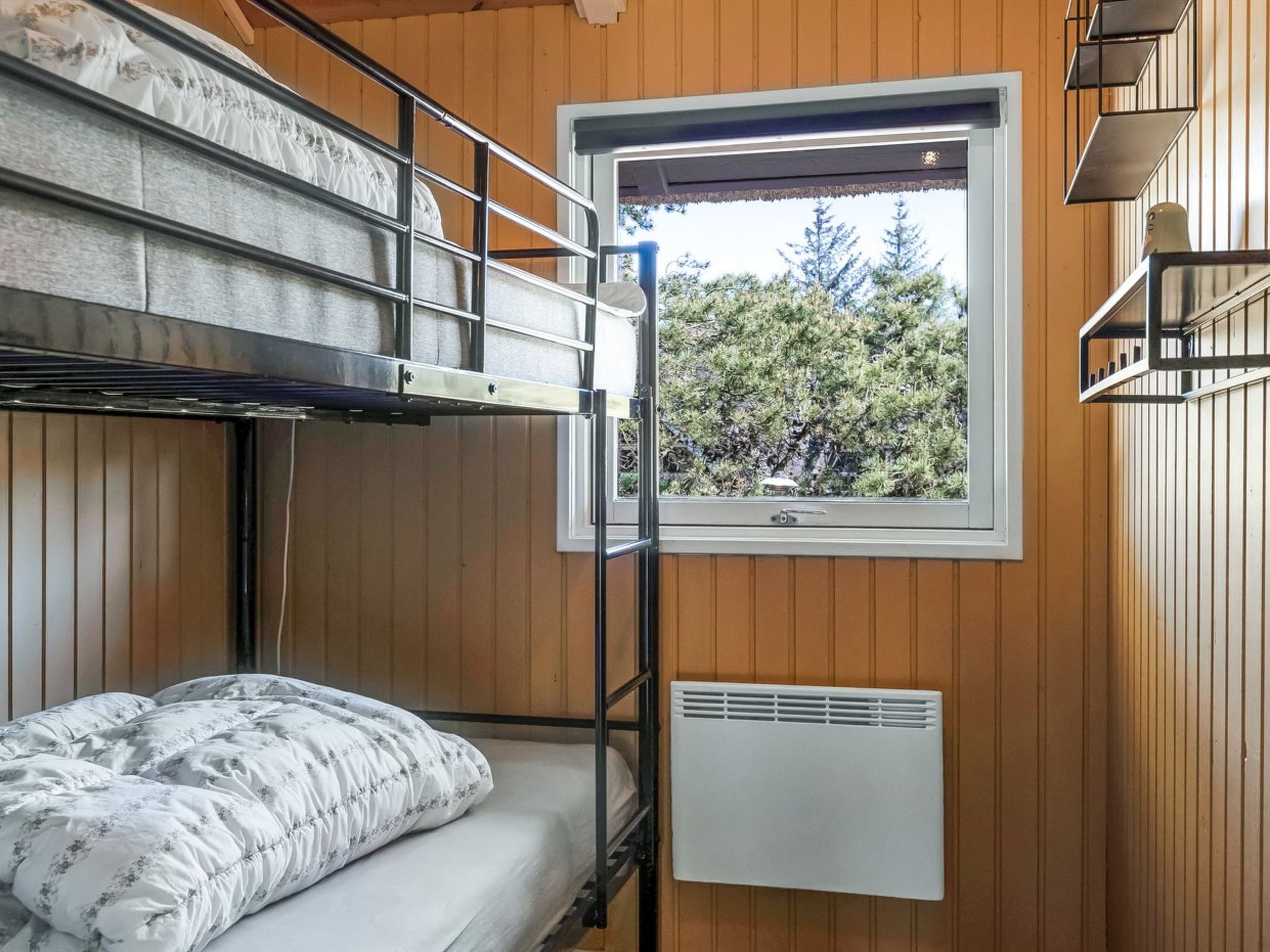 Een slaapkamer met stapelbed, raam en radiator.