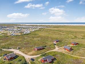 Kustgebied met een stacaravenpark en verschillende rode gebouwen, vermoedelijk accommodaties, met een strand op de achtergrond.