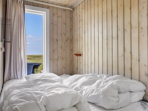 A room with a bed, a window with curtains, and a view of the outdoors.