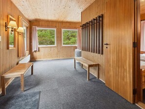 Ein Zimmer aus Holz mit zwei Bänken, einem Klavier und einem Fenster.