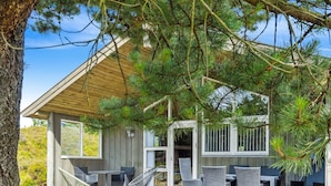 Une maison moderne dotée d’un patio couvert, aménagé avec du mobilier d’extérieur et une grande fenêtre.