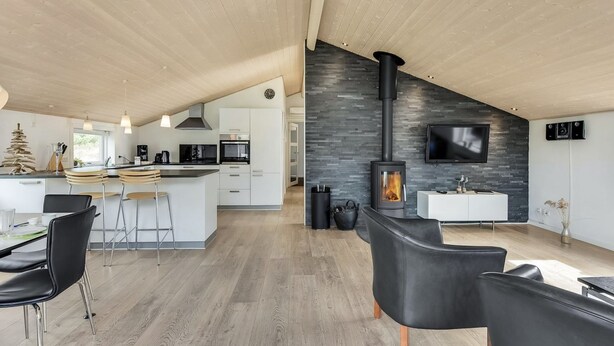 A modern kitchen with a central island, a dining area with black leather chairs, and a living area with a fireplace. - "Lav" - 3.8km from the sea by Interhome (Rømø)