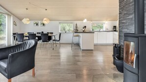 A modern kitchen with a central island, a dining area with black chairs, and a large black wood-burning stove. - "Lav" - 3.8km from the sea by Interhome (Rømø)