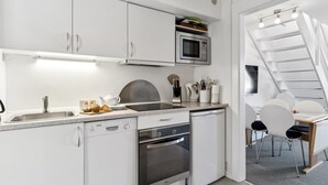 Une cuisine moderne avec des meubles blancs, un four à micro-ondes, un évier et un lave-vaisselle. Il y a également un coin repas avec une table et des chaises.