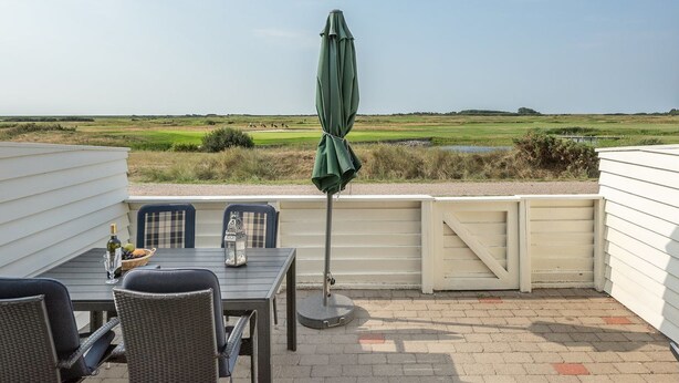 A patio with a table, chairs, and an umbrella overlooking a golf course. - "Helvig" - 2.3km from the sea by Interhome (Rømø)