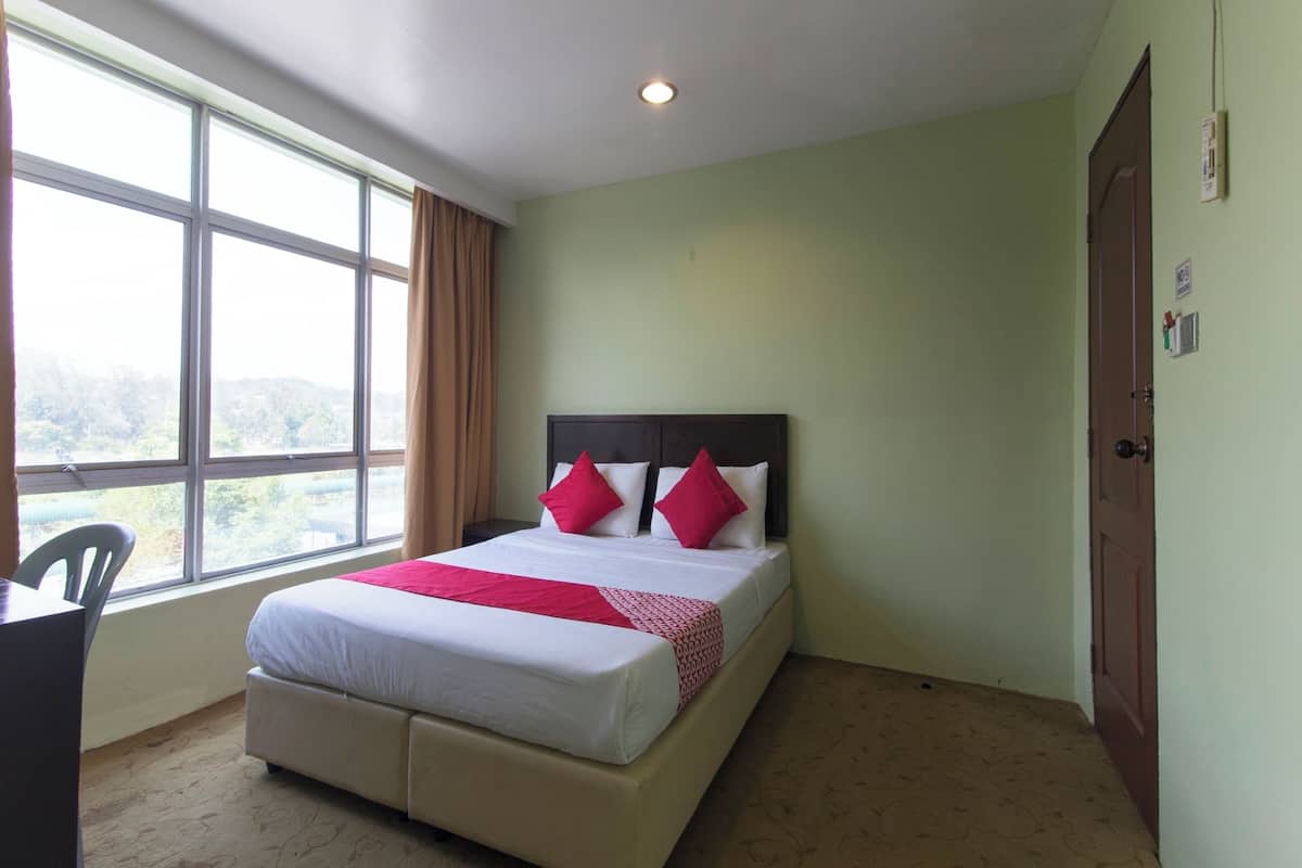 Una habitación de hotel con cama, escritorio y ventana con cortinas.