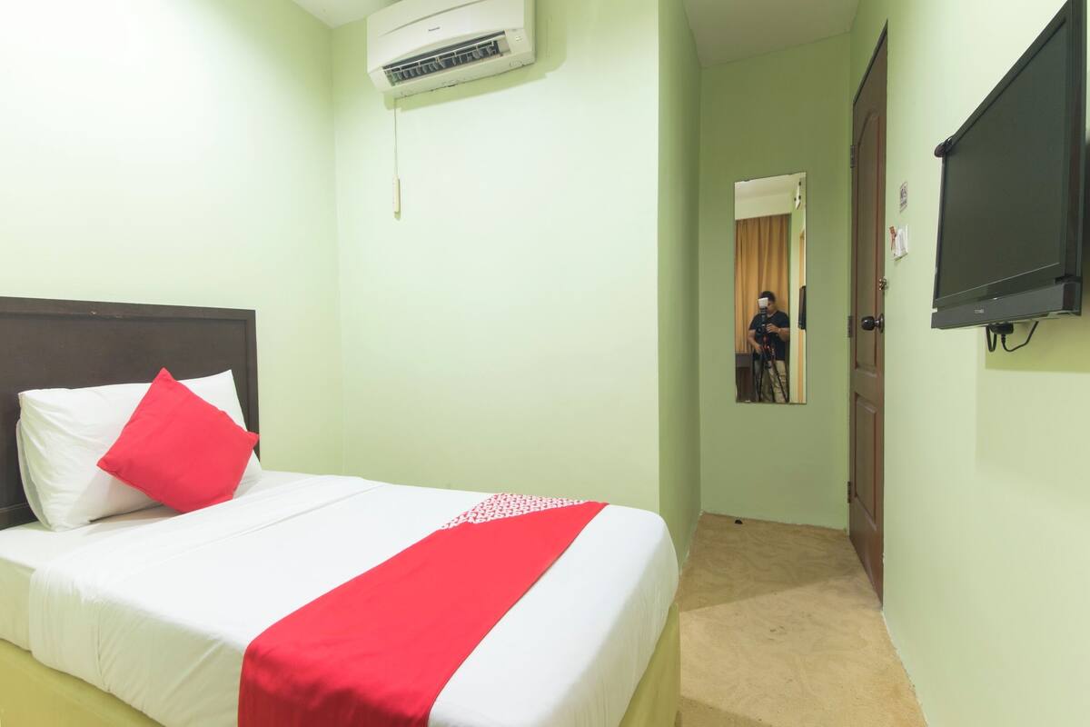 Una habitación de hotel con una cama, televisión y aire acondicionado.