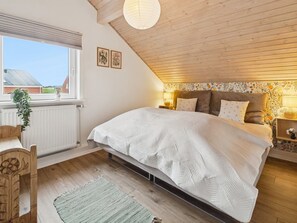 Une chambre avec un grand lit, un plafond en bois et une fenêtre donnant sur un beau paysage.