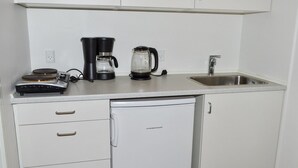 Een kleine keuken met een koffiezetapparaat, waterkoker en een spoelbak.